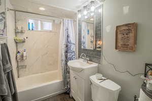 Bathroom with vanity, shower / bath combo, and dark wood finished floors