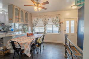 Dining space with dark wood-style flooring and ceiling fan