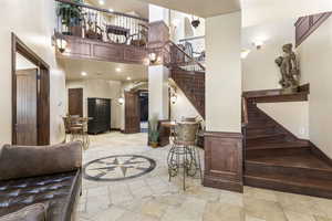 Living area featuring inlaid floor details, stairway, a high ceiling, light tile patterned floors, and recessed lighting
