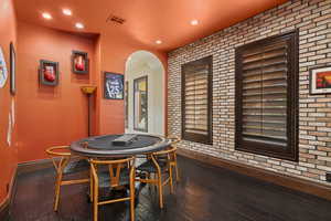 Game room featuring brick wall, dark wood-type flooring, and recessed lighting