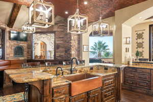 Kitchen featuring arched walkways, light stone countertops, a chandelier, hanging light fixtures, and recessed lighting