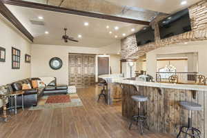 Kitchen with recessed lighting, dark wood finished floors, a kitchen bar, a chandelier, and light stone counters