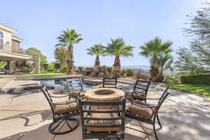 View of patio featuring a fire pit, a water view, and a pool with connected hot tub