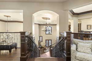 Corridor featuring a chandelier, an upstairs landing, crown molding, dark wood finished floors, and recessed lighting