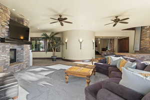 Carpeted living area featuring a fireplace, ceiling fan, and recessed lighting