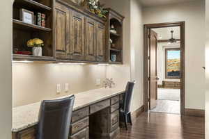 Bar area with built in study area, open shelves, dark brown cabinets, dark wood finished floors, and ceiling fan