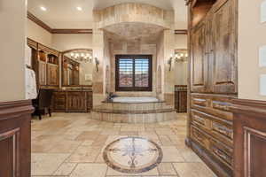 Full bathroom featuring crown molding, stone tile flooring, a chandelier, a bath, and vanity