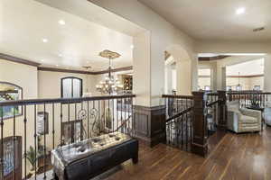 Hallway featuring a chandelier, an upstairs landing, dark wood-style flooring, recessed lighting, and ornamental molding