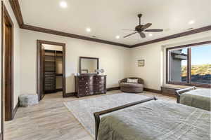 Bedroom with a spacious closet, ornamental molding, recessed lighting, ceiling fan, and light wood finished floors