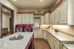 Laundry area featuring dark wood-style flooring, separate washer and dryer, cabinet space, and recessed lighting