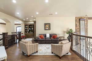 Living area featuring dark wood finished floors, recessed lighting, and arched walkways