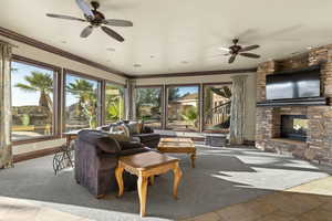 Carpeted living area with ornamental molding, a fireplace, tile patterned floors, a ceiling fan, and a water view