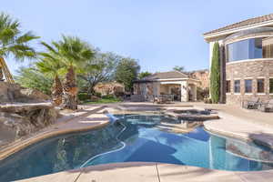 View of pool featuring a patio, a pool with connected hot tub, and a gazebo