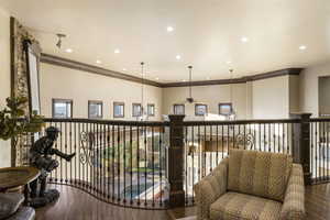 Hallway with wood finished floors, ornamental molding, recessed lighting, and a chandelier