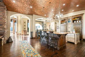 Kitchen featuring arched walkways, recessed lighting, decorative light fixtures, light stone countertops, and a breakfast bar