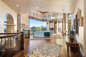 Living room with a glass covered fireplace, dark wood finished floors, crown molding, a towering ceiling, and recessed lighting