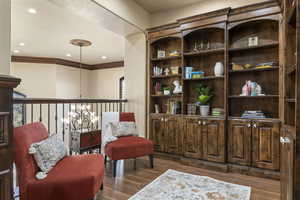 Living area featuring dark wood-style flooring, recessed lighting, and a chandelier