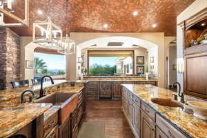 Kitchen with light stone counters, dark wood finished floors, hanging light fixtures, recessed lighting, and a breakfast bar