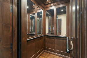 Elevator featuring crown molding and wood finished floors