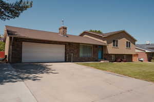 Split level home with brick siding, driveway, a front lawn, and shingle roof