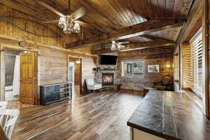 Living area with wooden walls, wood finished floors, ceiling fan, a fireplace, and wood ceiling