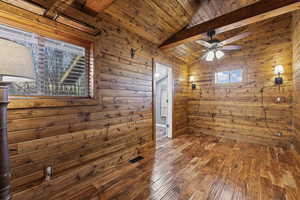 Empty room with wooden walls, wood-type flooring, wooden ceiling, and ceiling fan