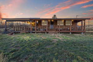 View of front facade featuring a front lawn, covered porch, and stone siding