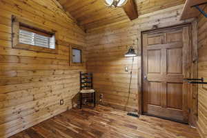 Interior space with wooden walls, wood ceiling, hardwood / wood-style flooring, and vaulted ceiling
