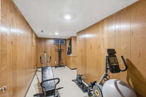 Workout area featuring wood walls and a textured ceiling