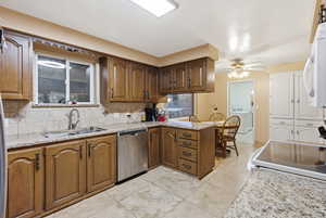 Kitchen featuring light stone counters, white appliances, backsplash, and a peninsula