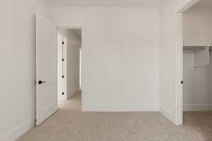 Unfurnished bedroom with light carpet and a walk in closet