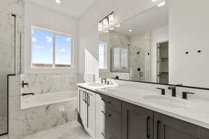 Bathroom featuring light marble finish floors, double vanity, healthy amount of natural light, a marble finish shower, and recessed lighting