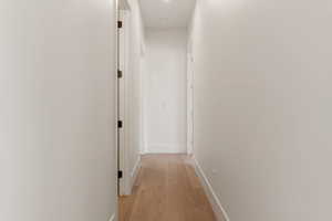 Corridor featuring baseboards and light wood-style flooring