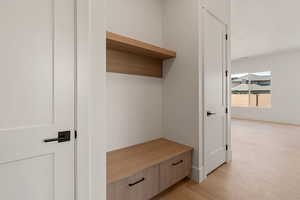 Mudroom featuring light wood-style flooring and baseboards