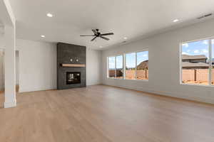Unfurnished living room with recessed lighting, a large fireplace, light wood-style flooring, and ceiling fan