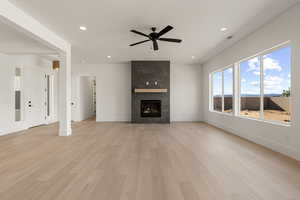 Unfurnished living room with light wood-style flooring, a premium fireplace, recessed lighting, and ceiling fan