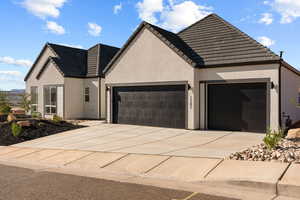 View of front facade with concrete driveway, stucco siding, and a garage