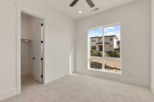 Unfurnished bedroom with light colored carpet, a spacious closet, recessed lighting, and a ceiling fan