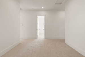 Unfurnished room with light colored carpet, attic access, and recessed lighting