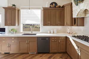 Kitchen featuring dishwasher, premium range hood, hanging light fixtures, black gas cooktop, and decorative backsplash