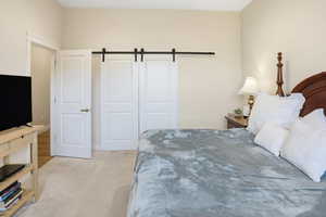 Bedroom with a barn door and light colored carpet