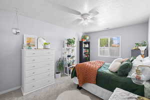 Carpeted bedroom featuring a textured ceiling and a ceiling fan