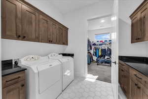 Washroom featuring cabinet space, light tile patterned floors, light carpet, and washing machine and dryer