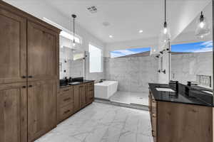 Bathroom with two vanities, light marble finish floors, tile walls, a freestanding tub, and a walk in shower
