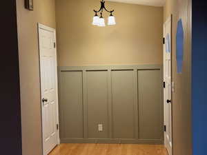 Hall with a decorative wall, wainscoting, and light wood finished floors