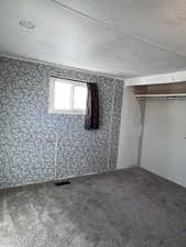 Second bedroom with a textured ceiling, carpet flooring, and a closet