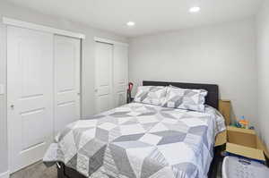 Bedroom with two closets, recessed lighting, and dark colored carpet