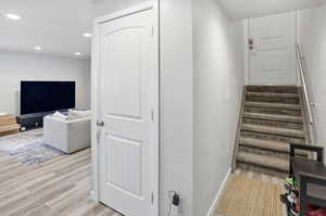 Stairs with a textured wall, wood finished floors, and recessed lighting