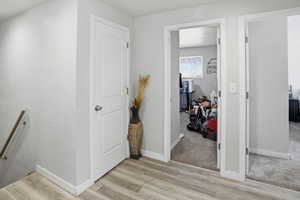 Hall with light wood-style flooring, light colored carpet, and an upstairs landing