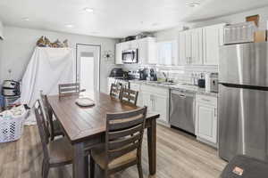 Kitchen featuring stainless steel appliances, white cabinetry, light stone countertops, tasteful backsplash, and a textured ceiling